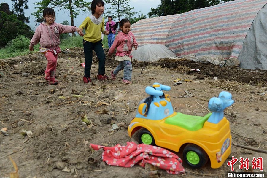 4月21日，四川雅安蘆山縣龍門鄉(xiāng)三個(gè)小孩在一輛玩具車前走過(guò)。中新社發(fā) 張?jiān)?攝