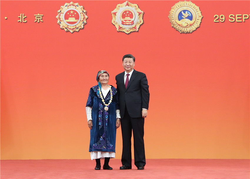 9月29日，中華人民共和國國家勛章和國家榮譽稱號頒授儀式在北京人民大會堂金色大廳隆重舉行。中共中央總書記、國家主席、中央軍委主席習近平向“人民楷模”國家榮譽稱號獲得者布茹瑪汗·毛勒朵頒授獎章。 新華社記者 王曄 攝